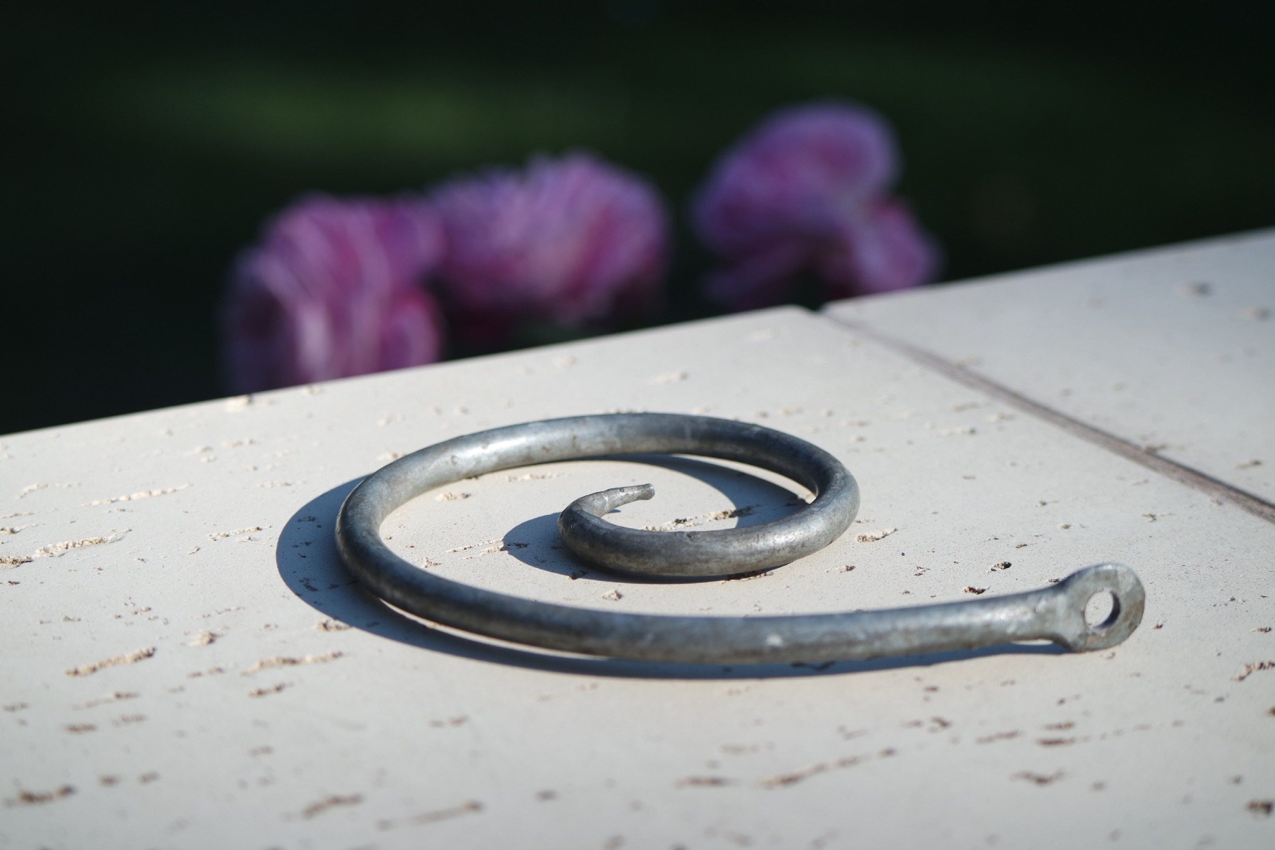 Rosenlocke Rankhilfe auf heller Fläche vor zartrosa Rosen